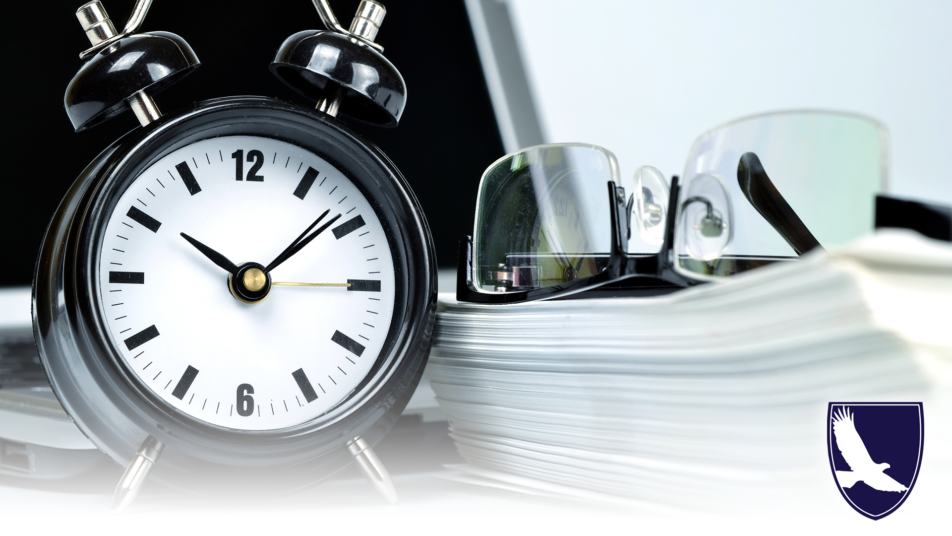 Clock, documents and a pair of glasses on a desk